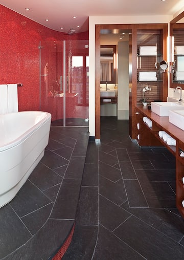 a bathroom with a red wall and a tub