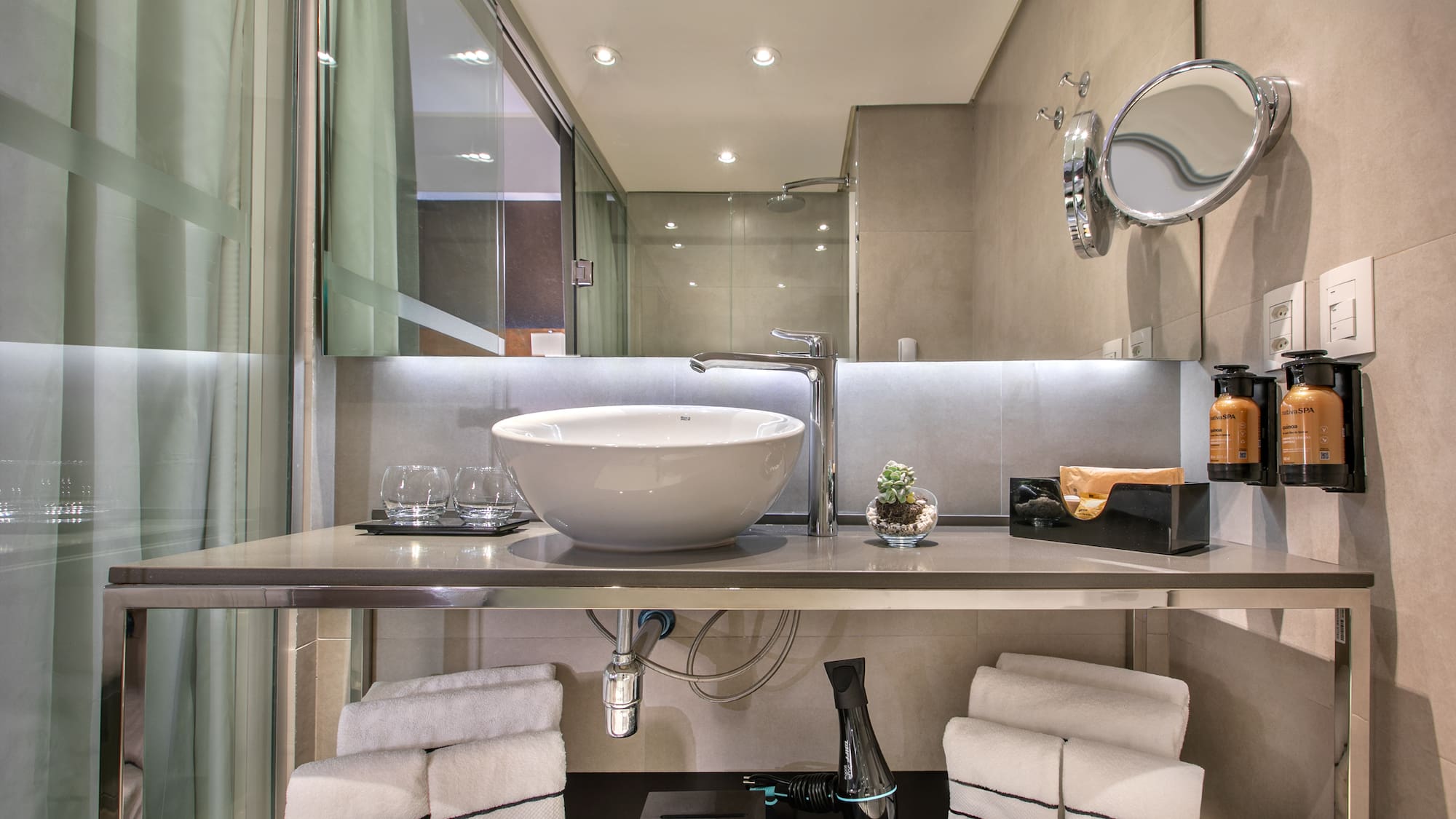 Banheiro moderno com pia de cuba branca sobre bancada de inox, espelho e toalhas organizadas. - Grand Premium - Meliá Ibirapuera, São Paulo