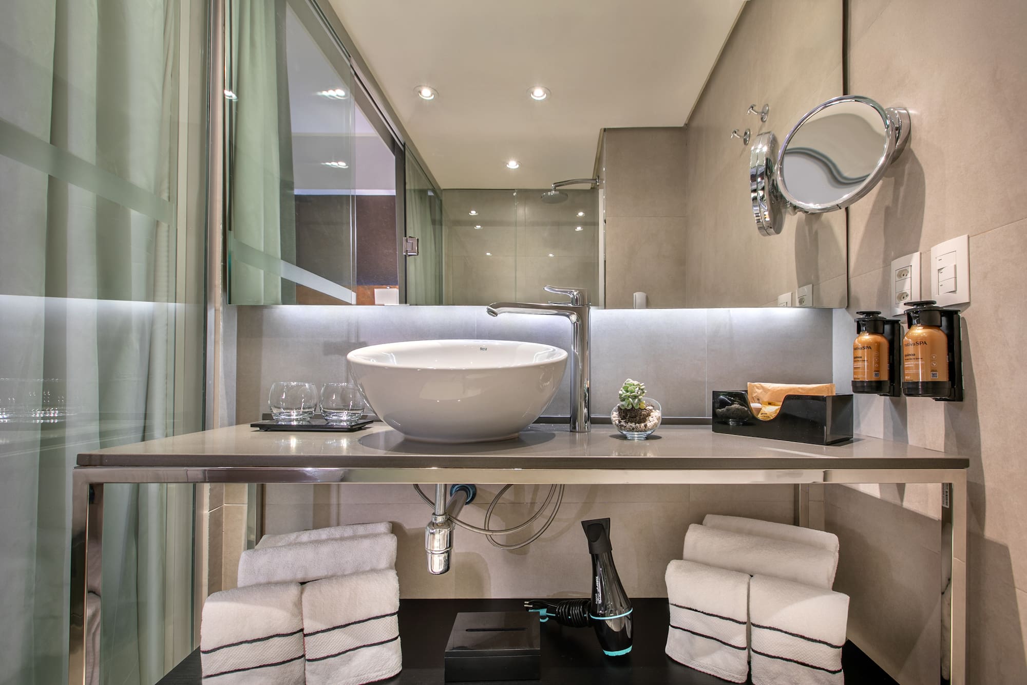 Banheiro moderno com pia de cuba branca sobre bancada de inox, espelho e toalhas organizadas. - Grand Premium - Meliá Ibirapuera, São Paulo