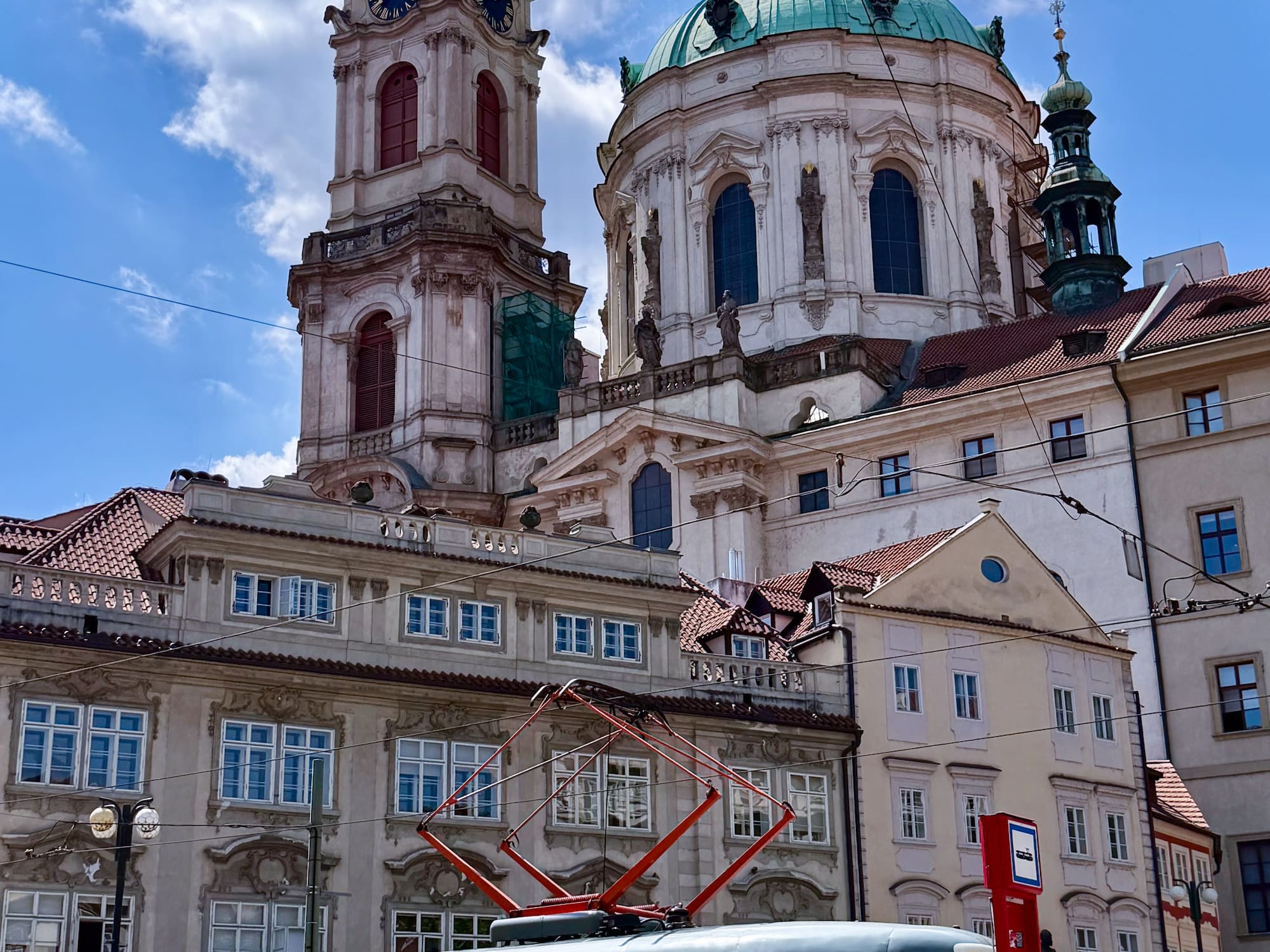 Red and white Prague tram in front of historic St. Nicholas Church.