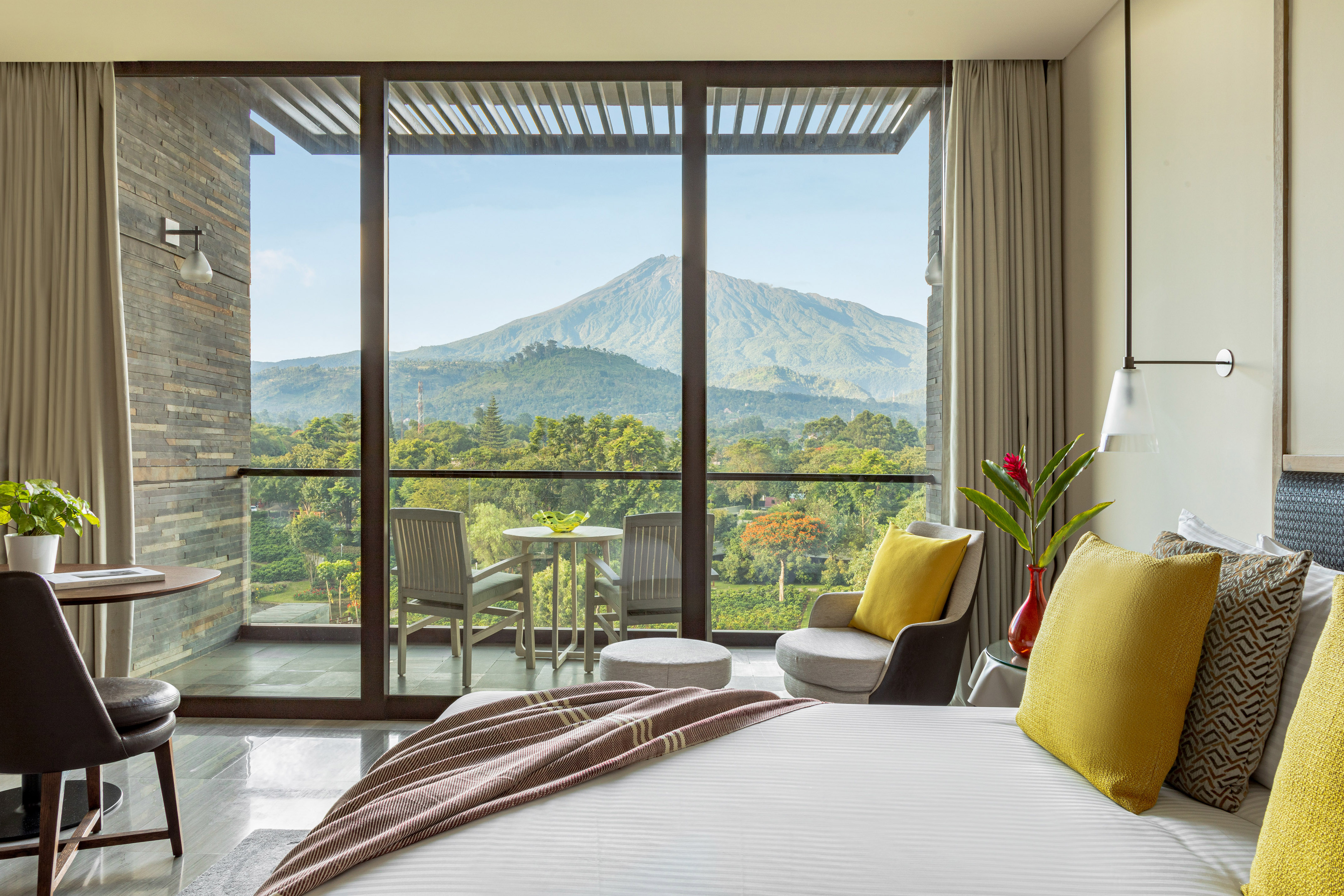 Hotel room with bed, private balcony, and volcanic mountain view.
