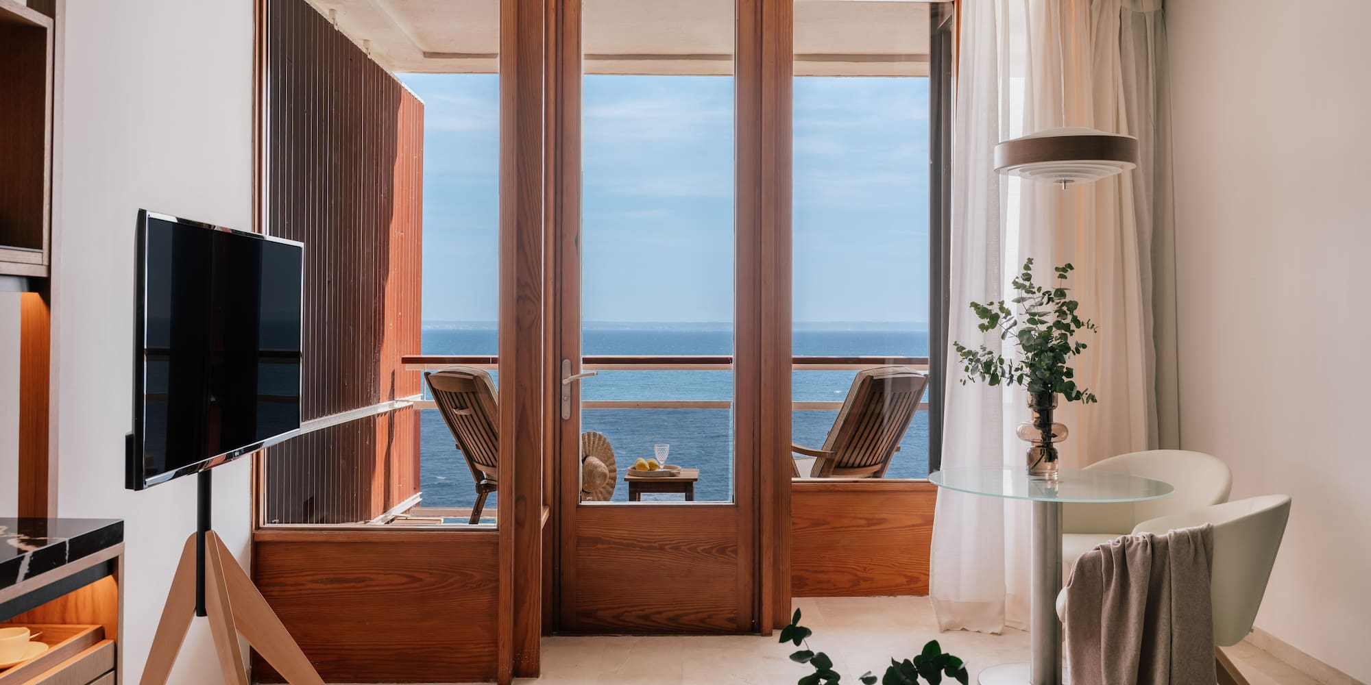 a room with a television and a view of the ocean