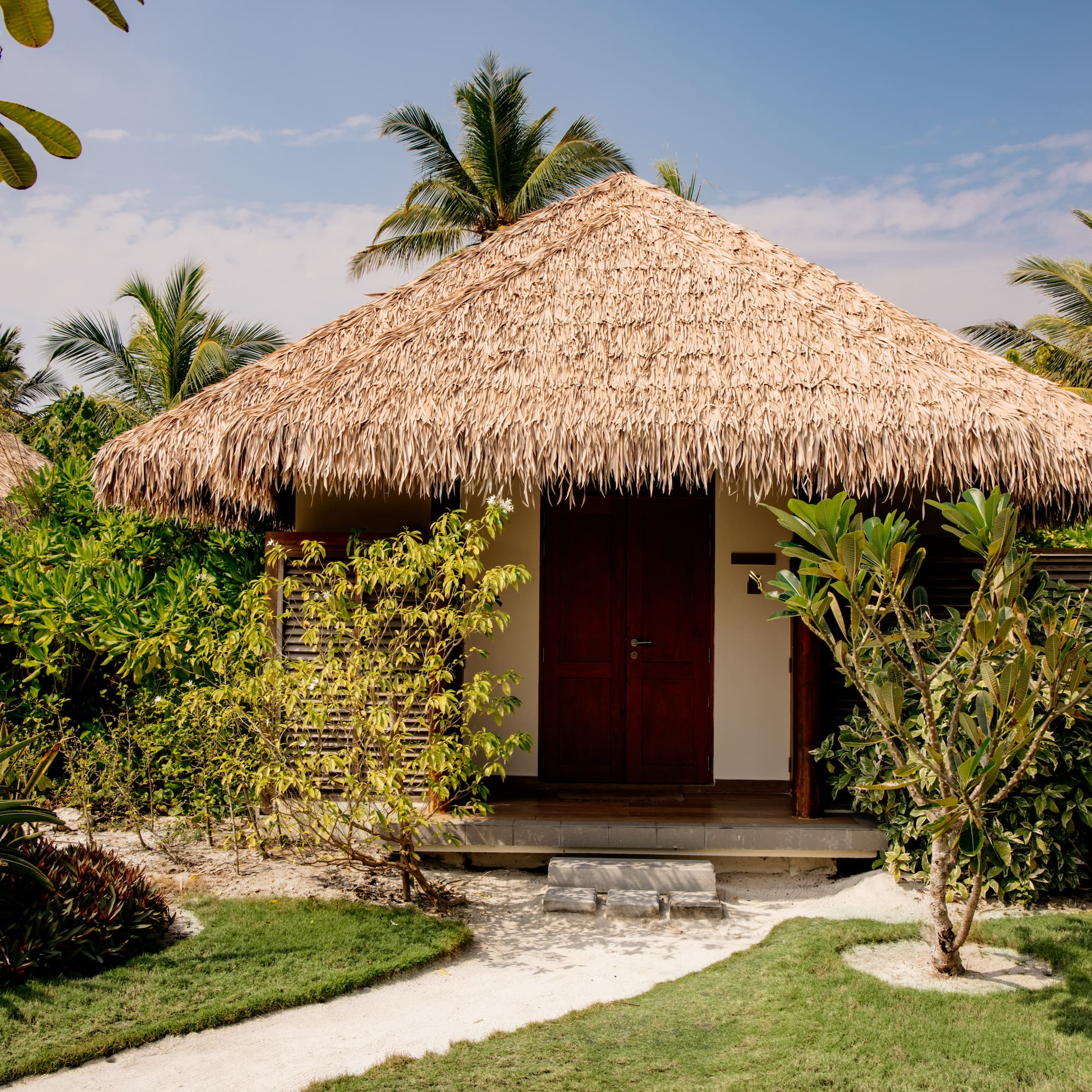 a small hut with grass roof and trees