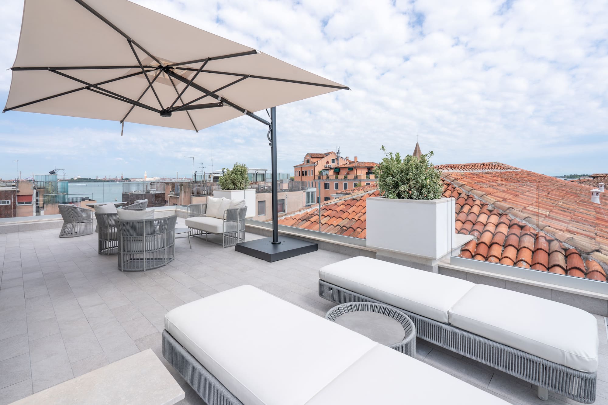 Rooftop terrace in Venice with sun loungers, umbrella, and cityscape.