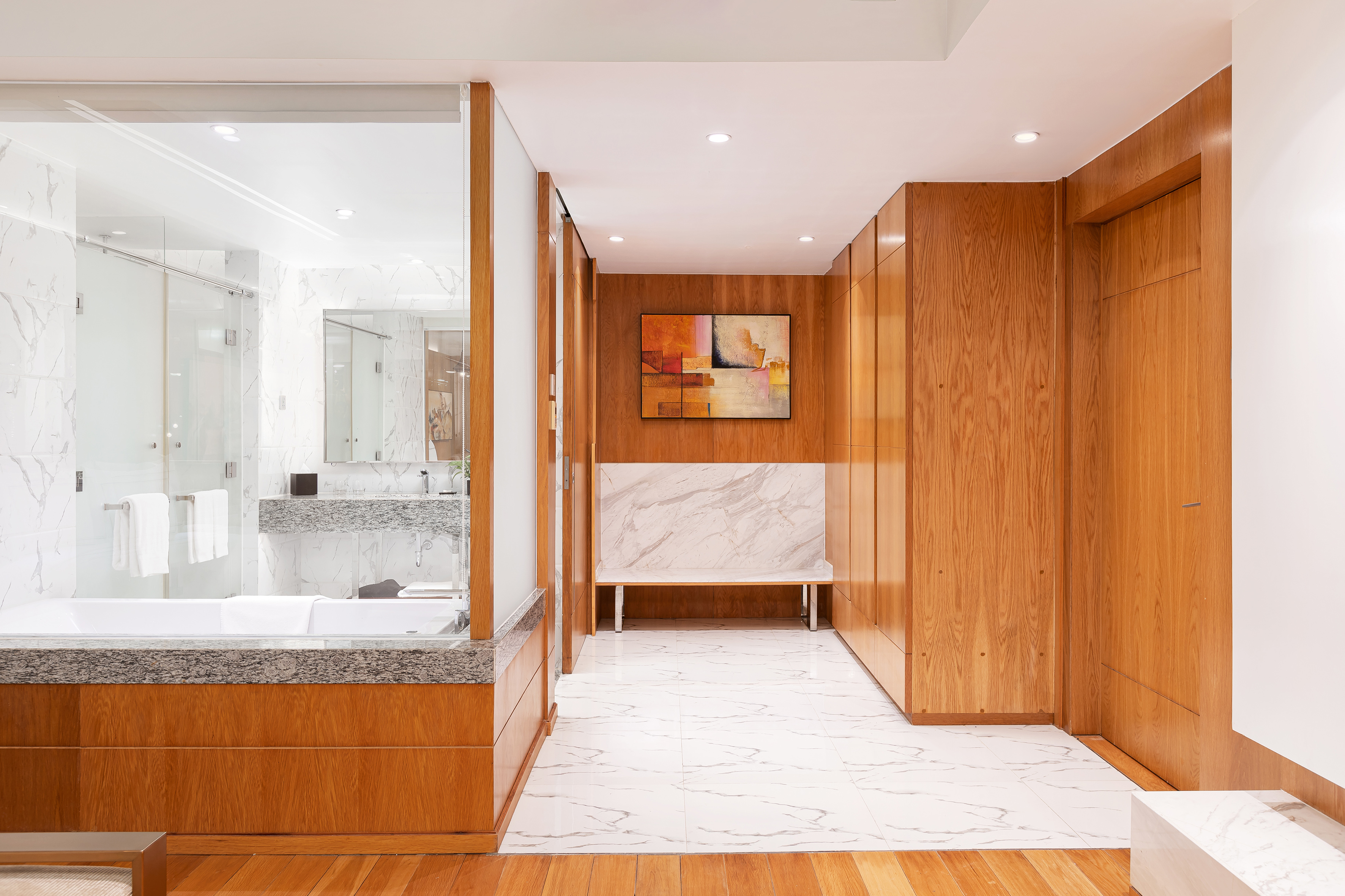 Modern luxury bathroom suite with marble, glass, and rich wood details.