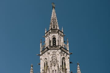 Ornate Gothic clock tower, Neues Rathaus, Munich, against blue sky.