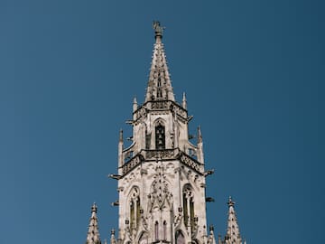 Ornate Gothic clock tower, Neues Rathaus, Munich, against blue sky.