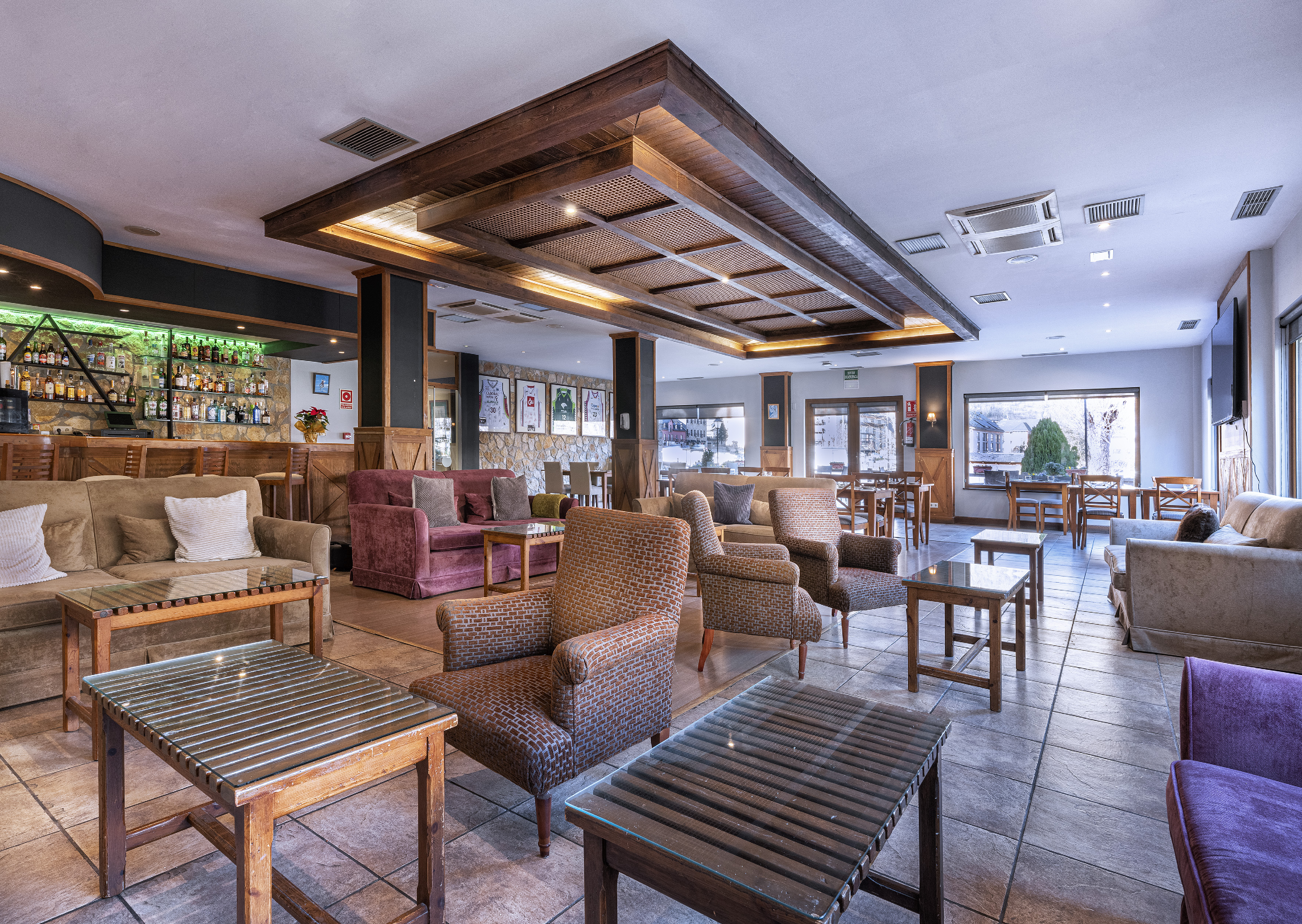 Cozy hotel lounge and bar with sofas, armchairs, and rustic wooden decor.