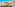 Sunny coastal town with turquoise sea, beach, palm trees, and diverse buildings.