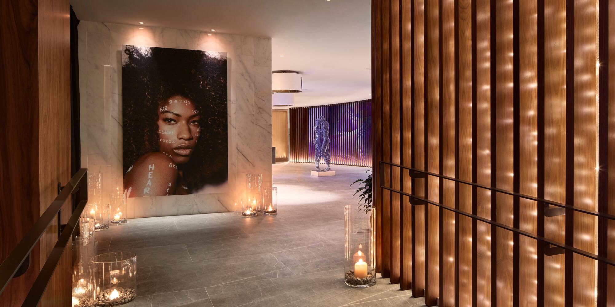 a large poster of a woman on a wall with candles