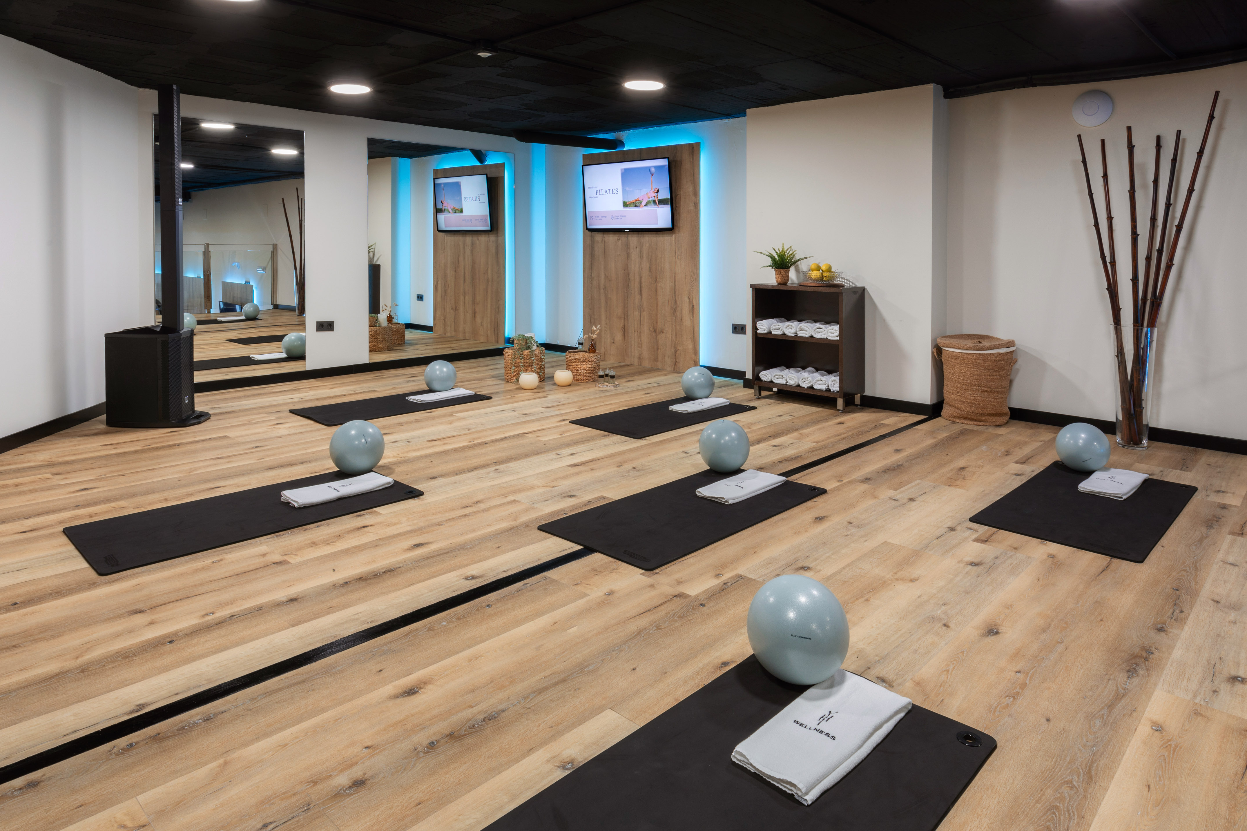 Modern pilates/yoga studio with exercise mats, balls, and wellness towels.