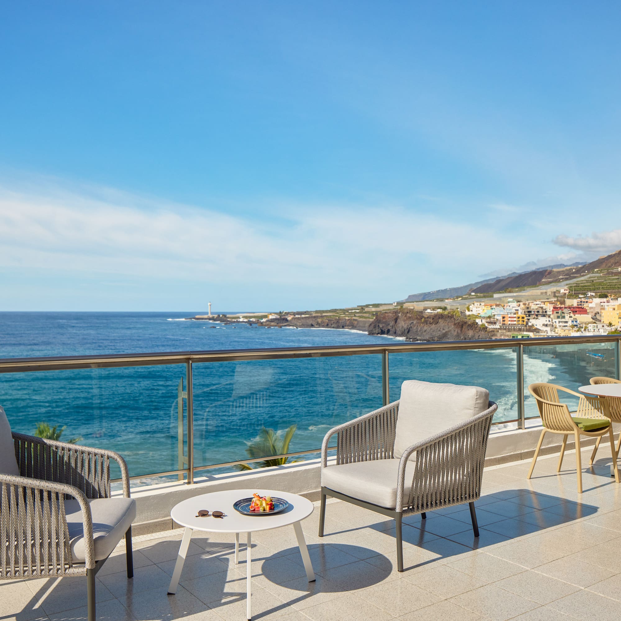 a patio with chairs and table overlooking the ocean