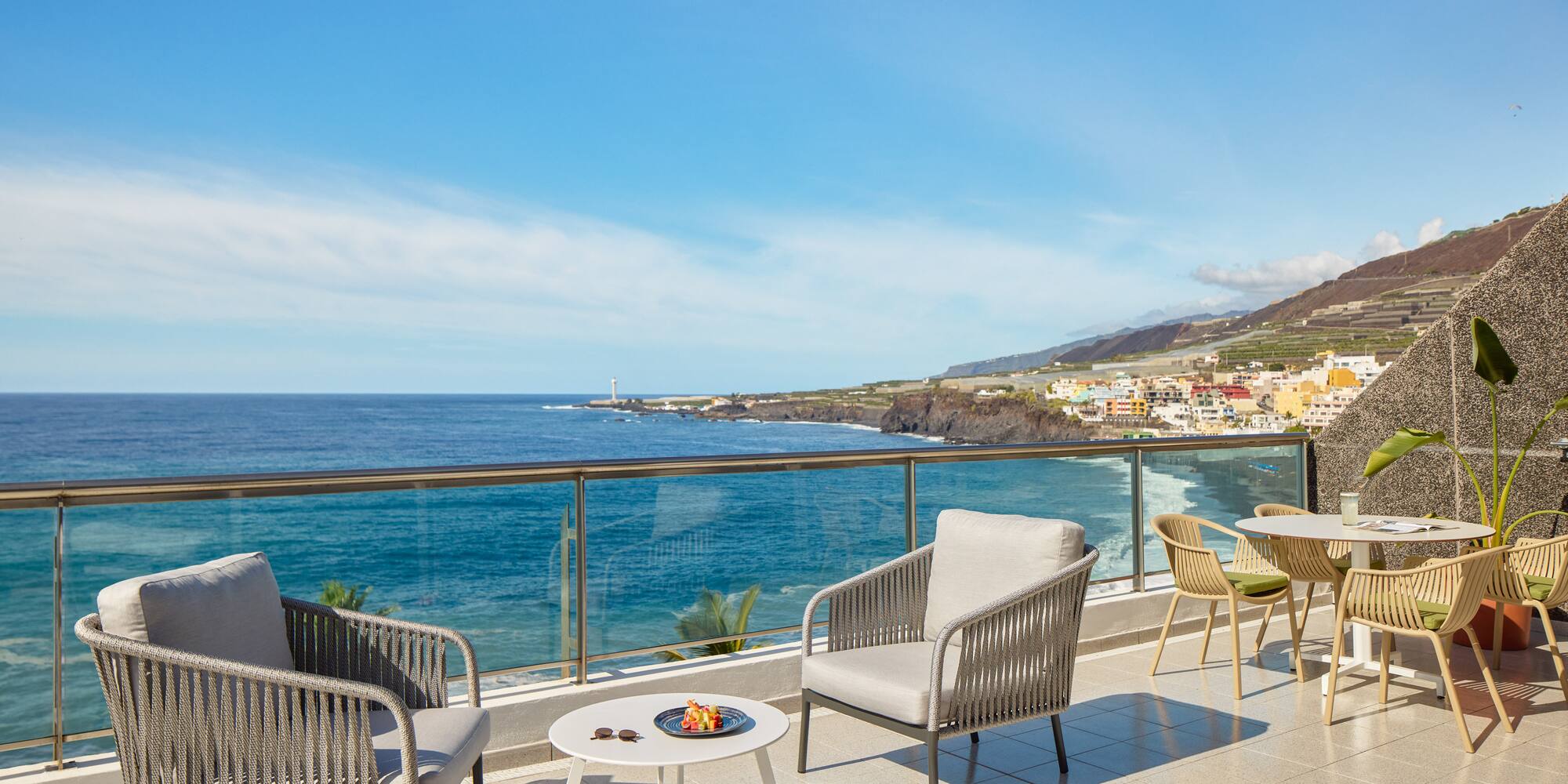 a patio with chairs and table overlooking the ocean