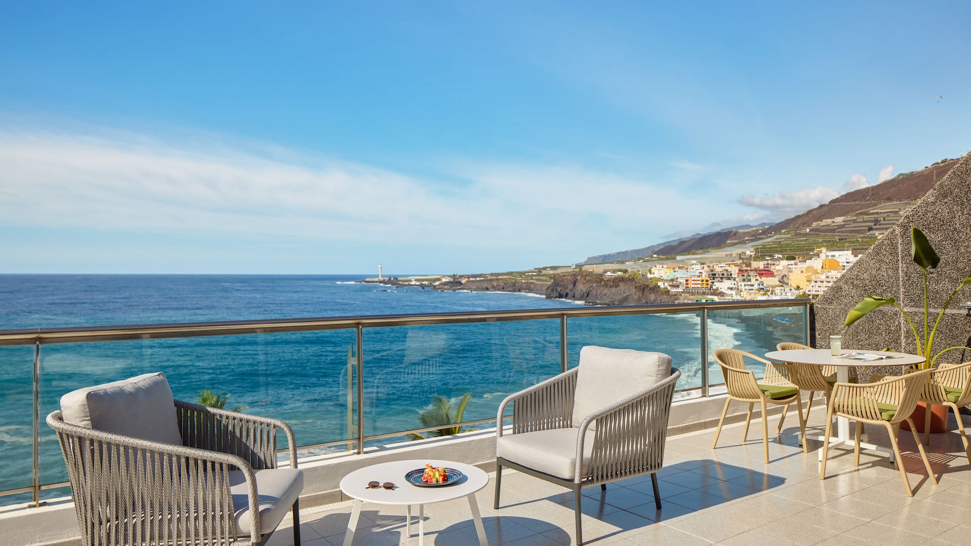 a patio with chairs and table overlooking the ocean