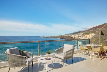 a patio with chairs and table overlooking the ocean