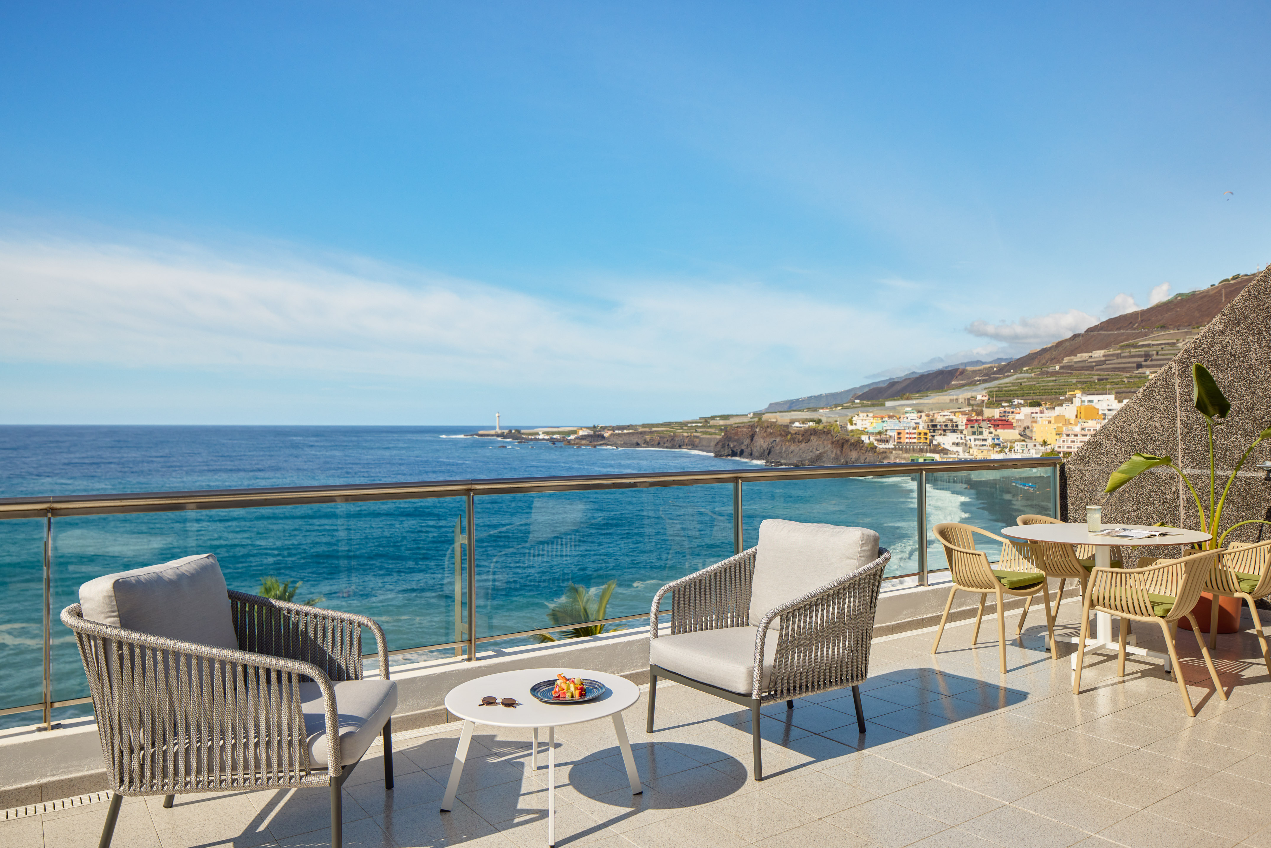 Ocean view terrace with modern outdoor seating, coastal town, and lighthouse.