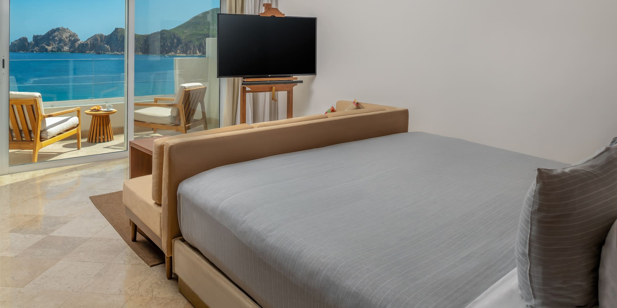 a bed with a television in a room with a view of the ocean