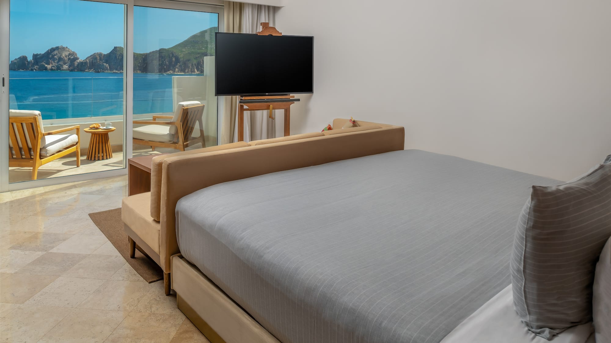 a bed with a television in a room with a view of the ocean