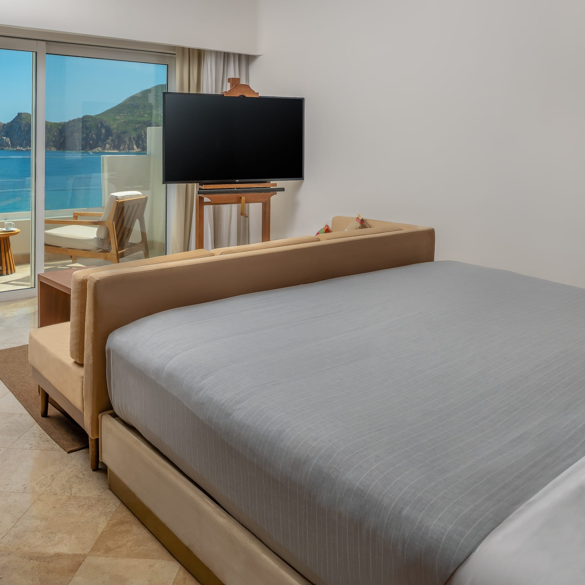 a bed with a television in a room with a view of the ocean