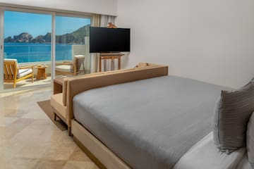 a bed with a television in a room with a view of the ocean