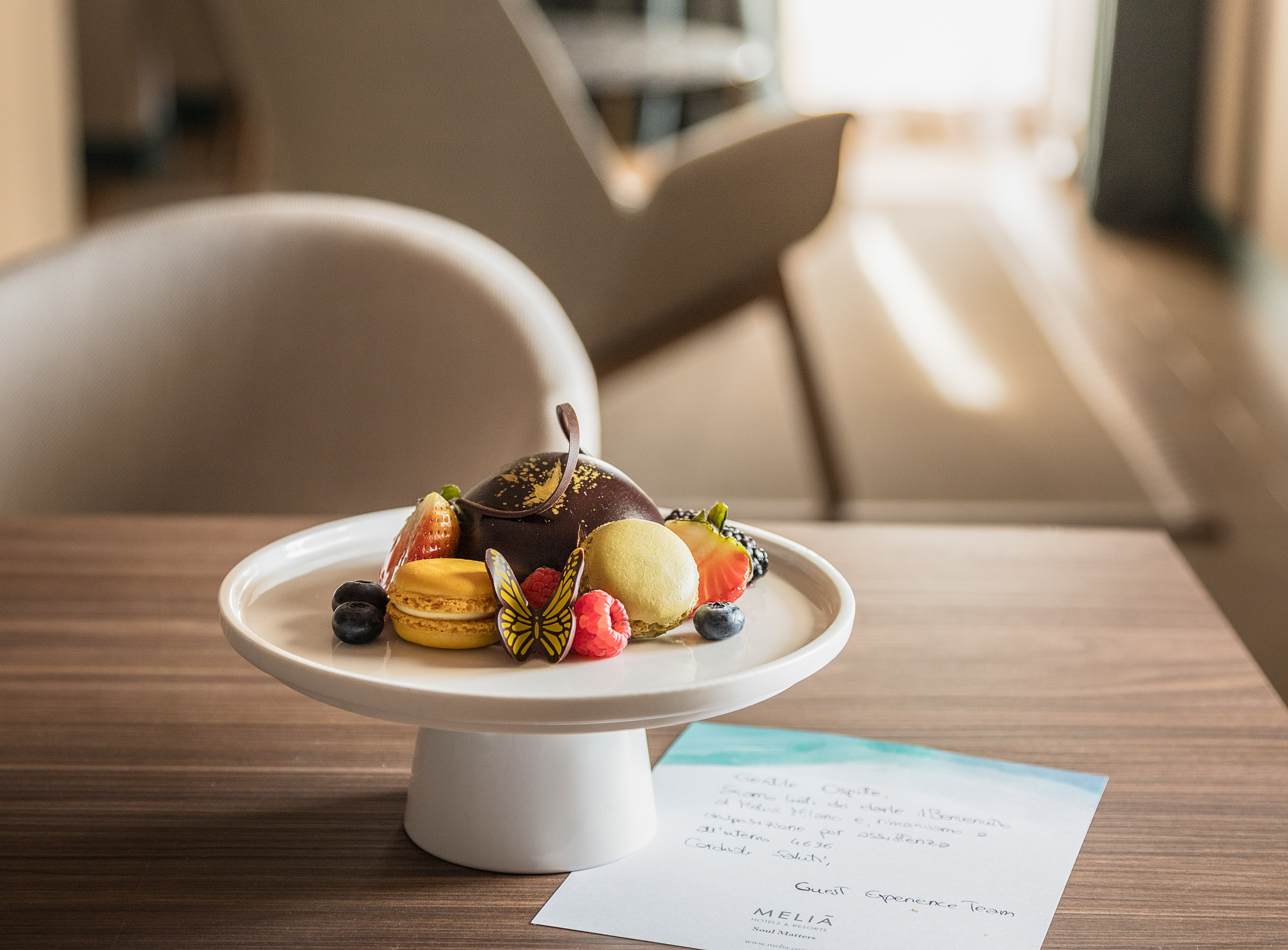 Meliá Hotels welcome dessert: chocolate, macarons, fresh berries on a stand.