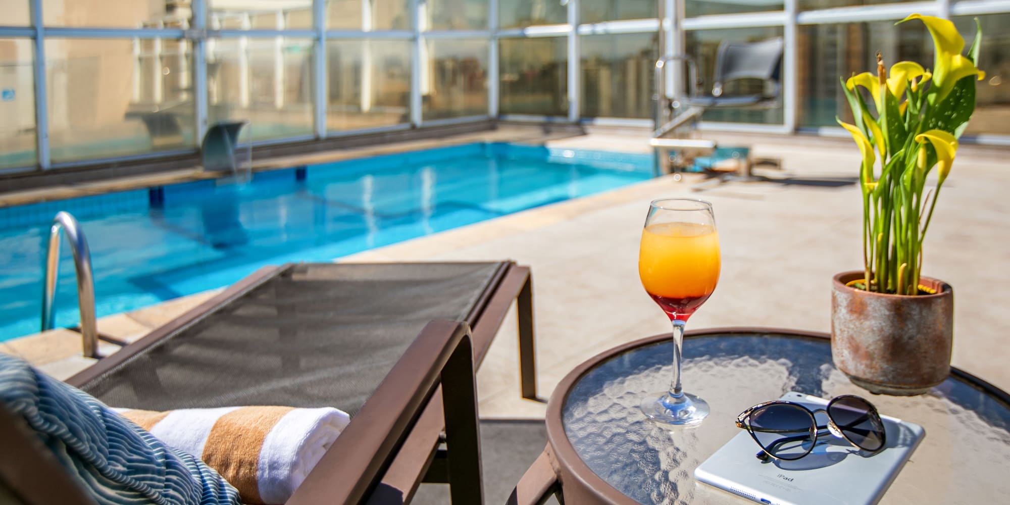 a pool with a glass of drink and a book on a table