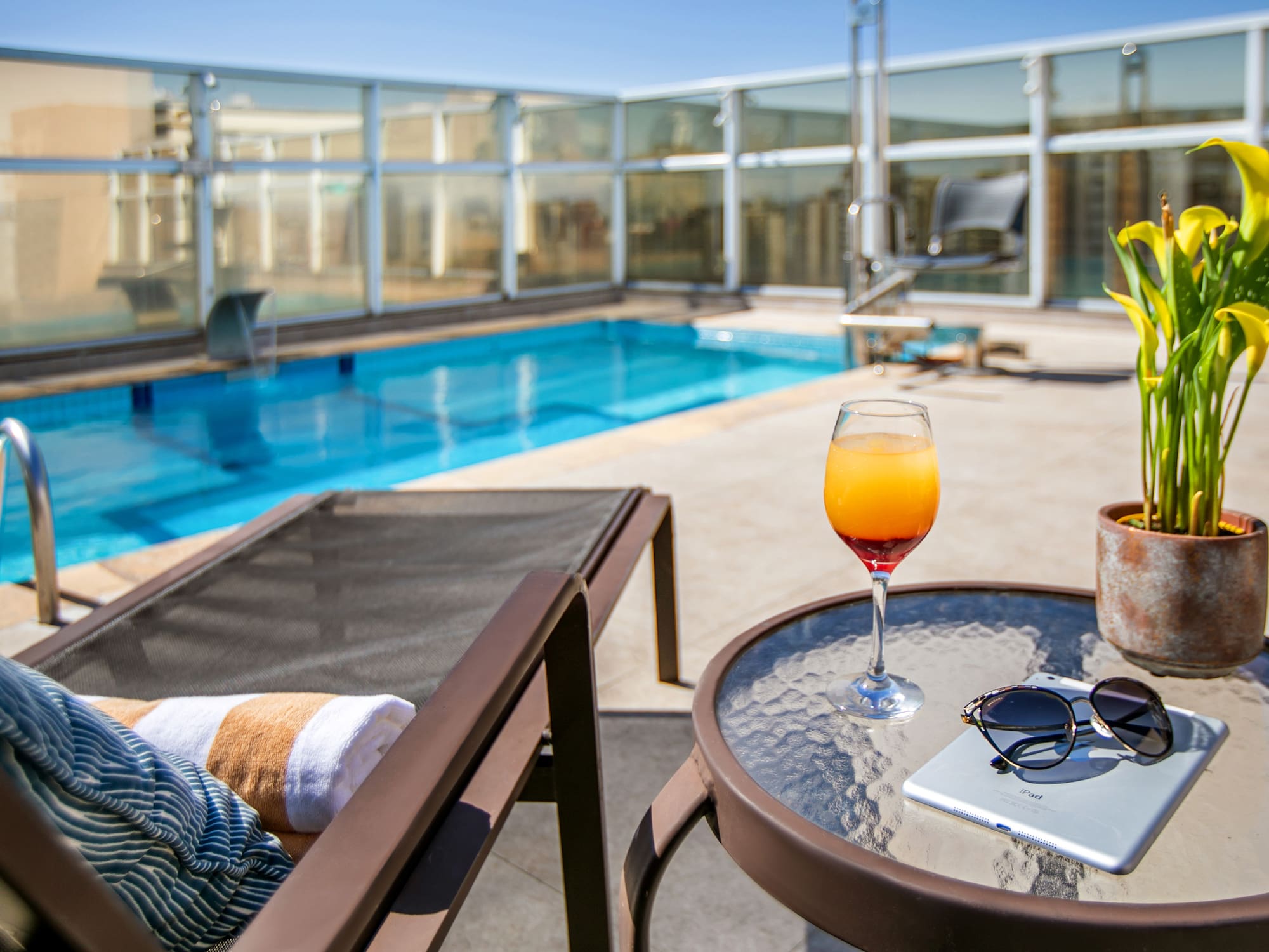 a pool with a glass of drink and a book on a table