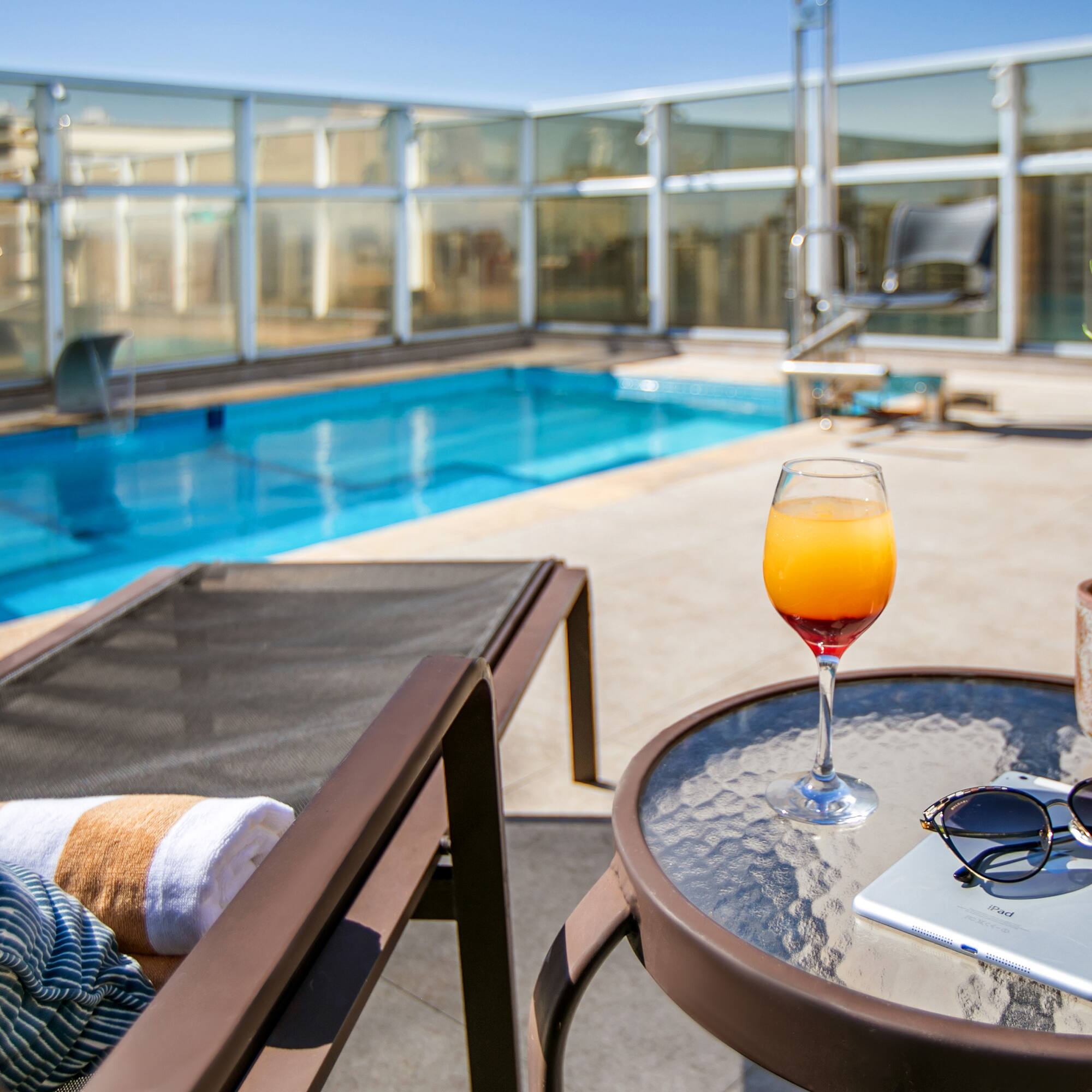 a pool with a glass of drink and a book on a table