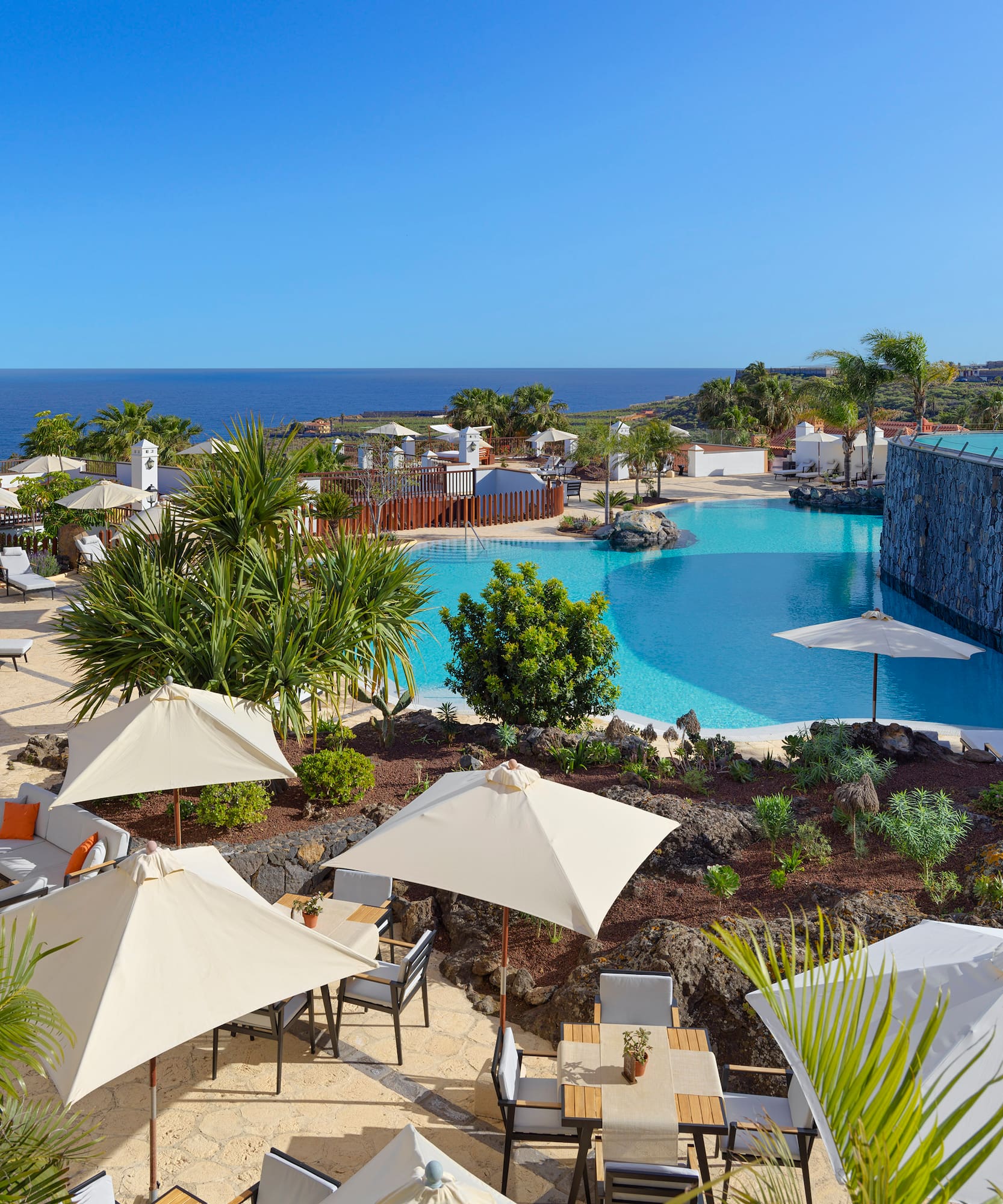 a pool with umbrellas and chairs and a stone wall