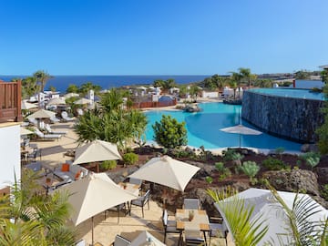 a pool with umbrellas and chairs and a stone wall