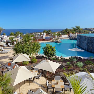 a pool with umbrellas and chairs and a stone wall