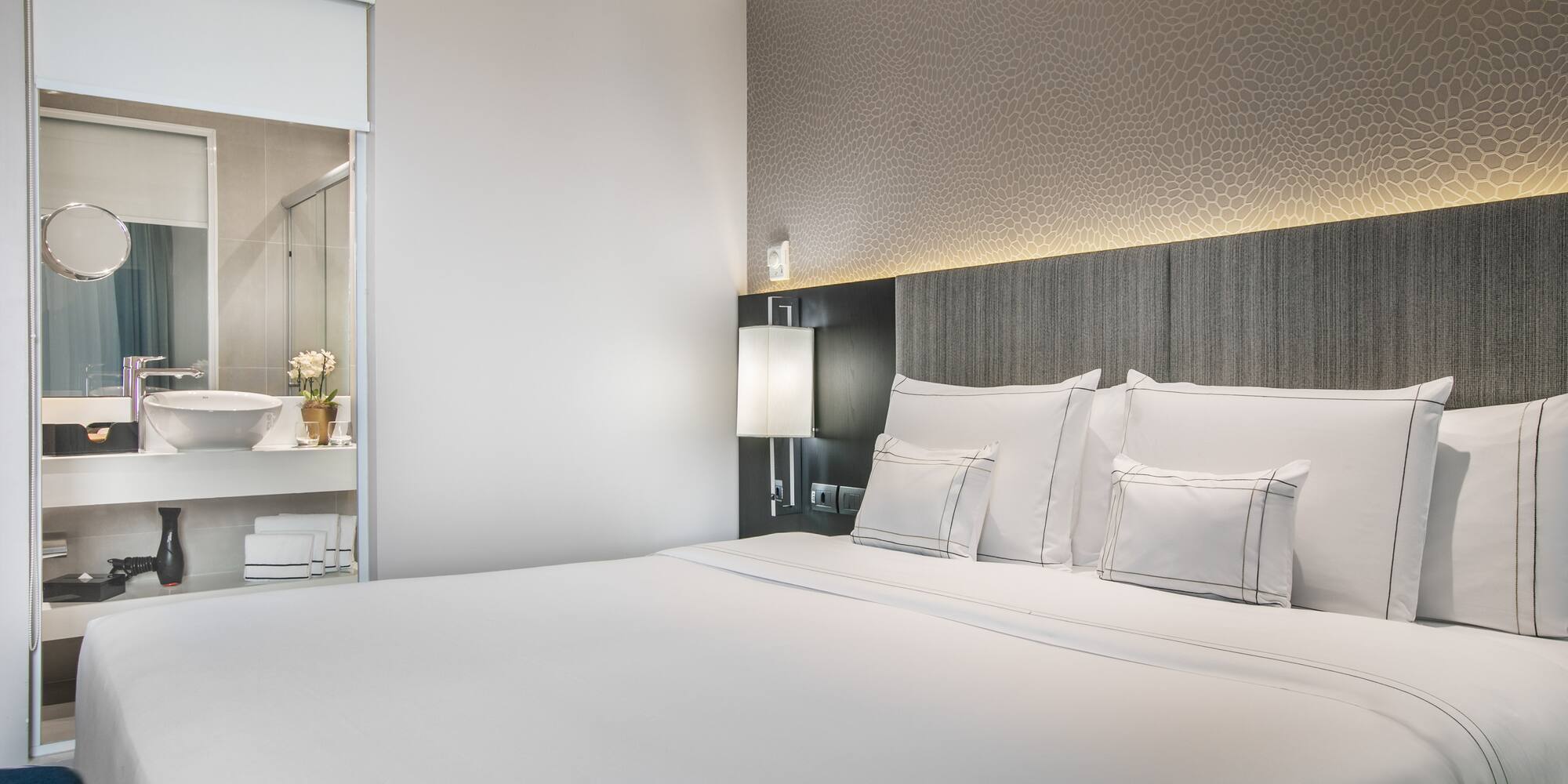 a bed with white sheets and pillows