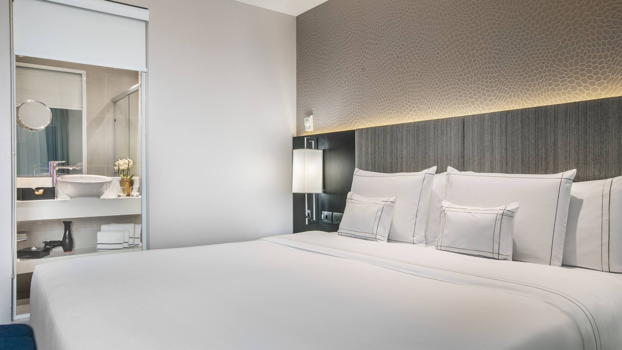 a bed with white sheets and pillows