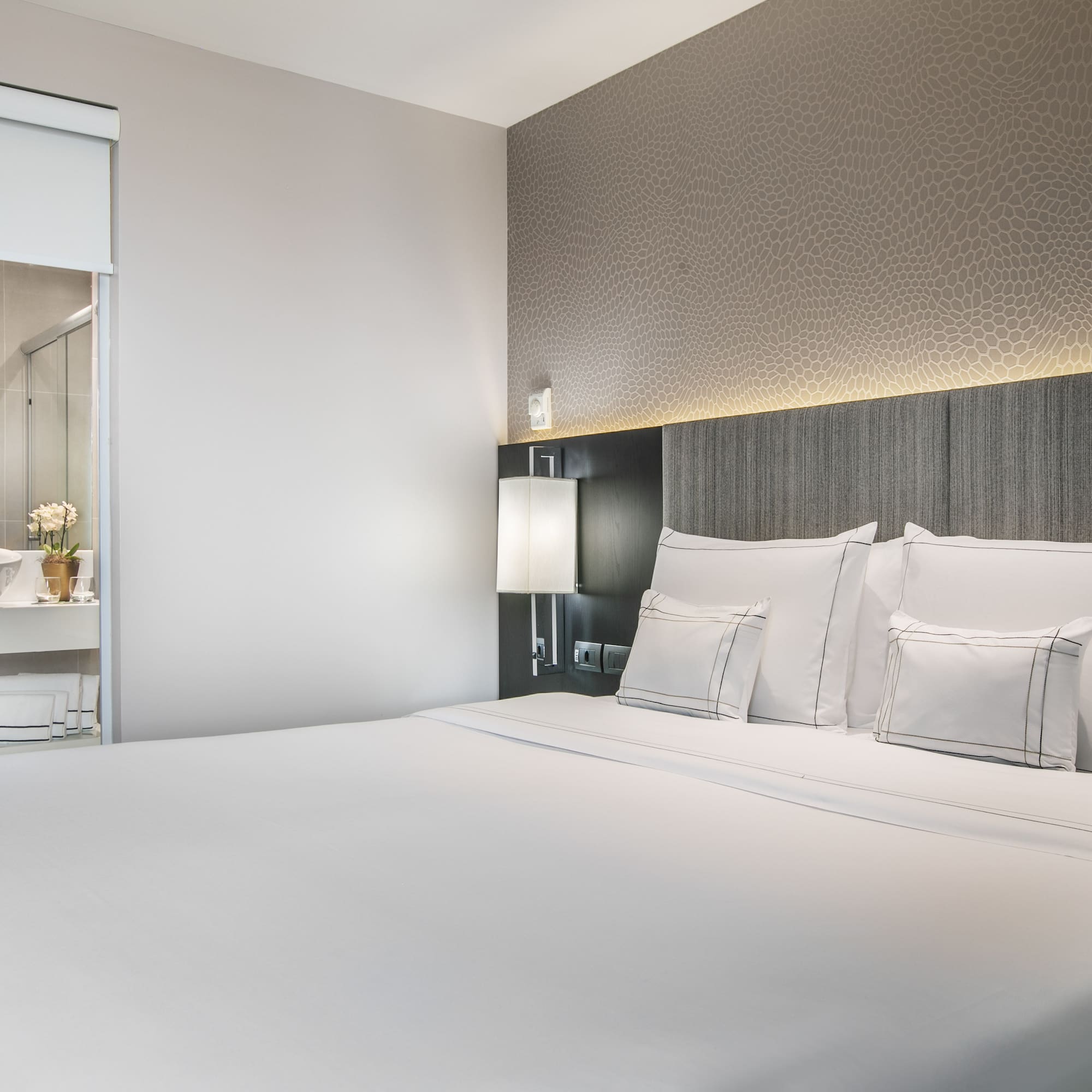 a bed with white sheets and pillows