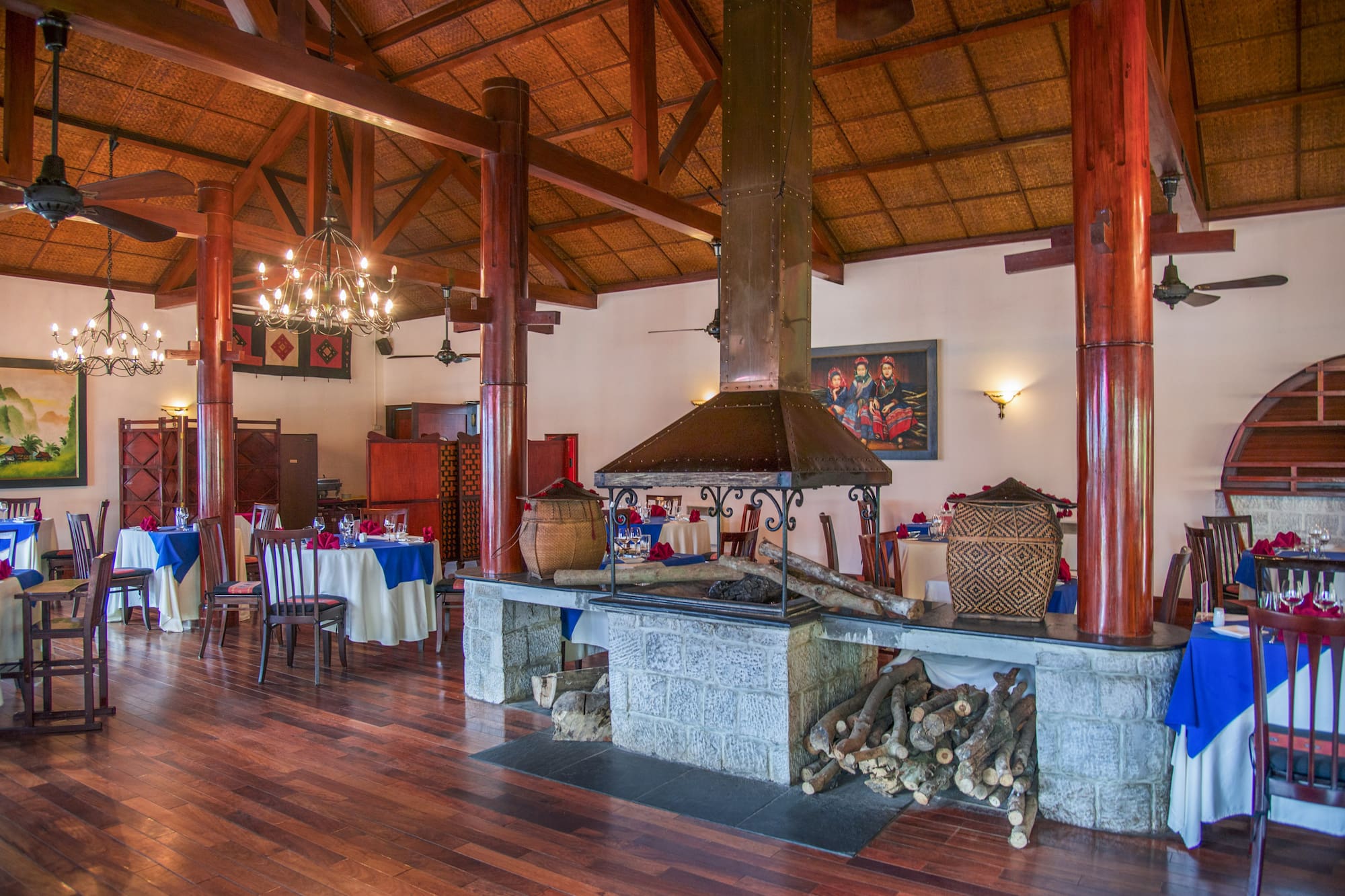 Restaurant dining room with stone fireplace, wooden ceiling, and set tables.
