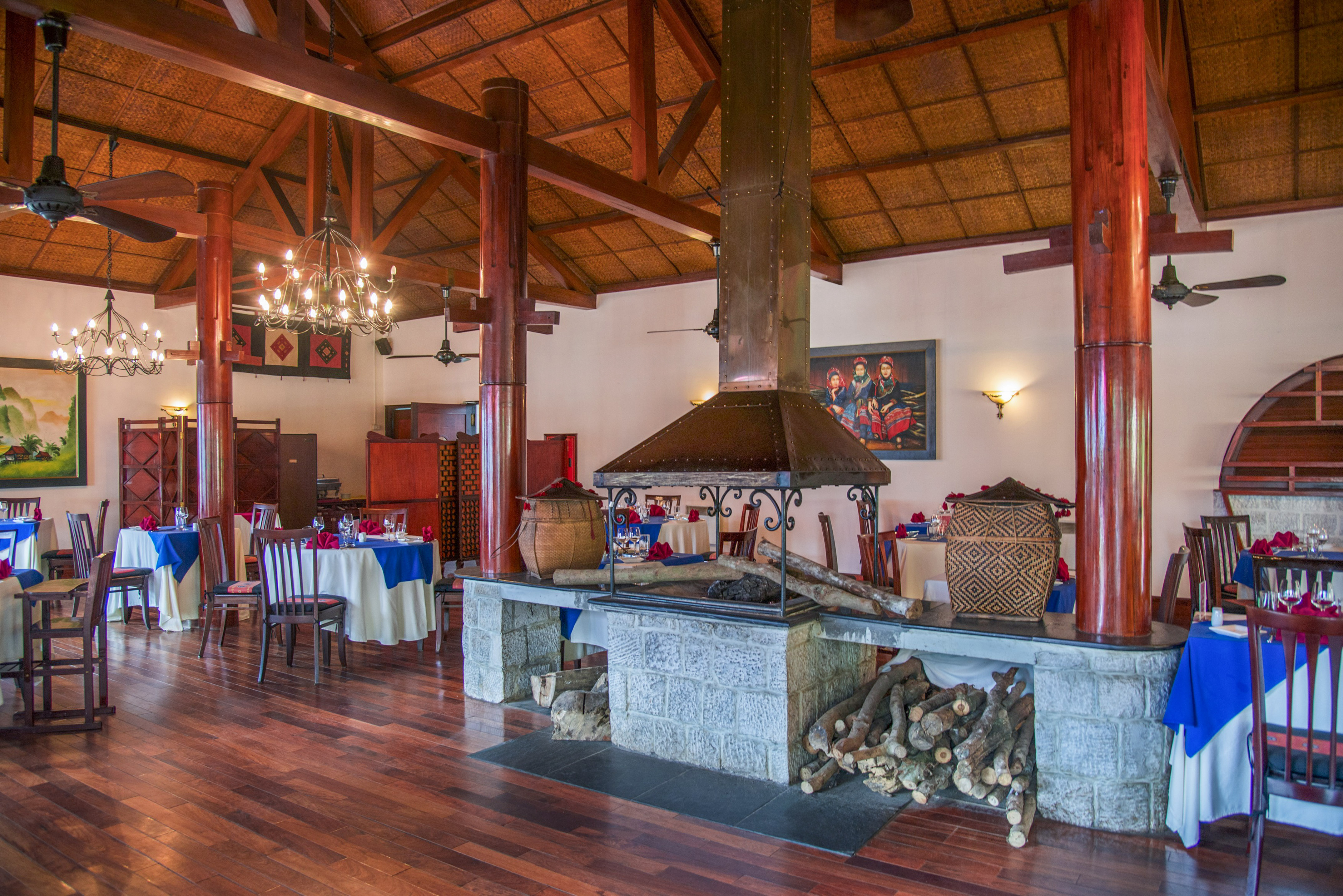 Restaurant dining room with stone fireplace, wooden ceiling, and set tables.