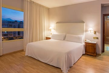 a bed with white sheets and lamps in a room