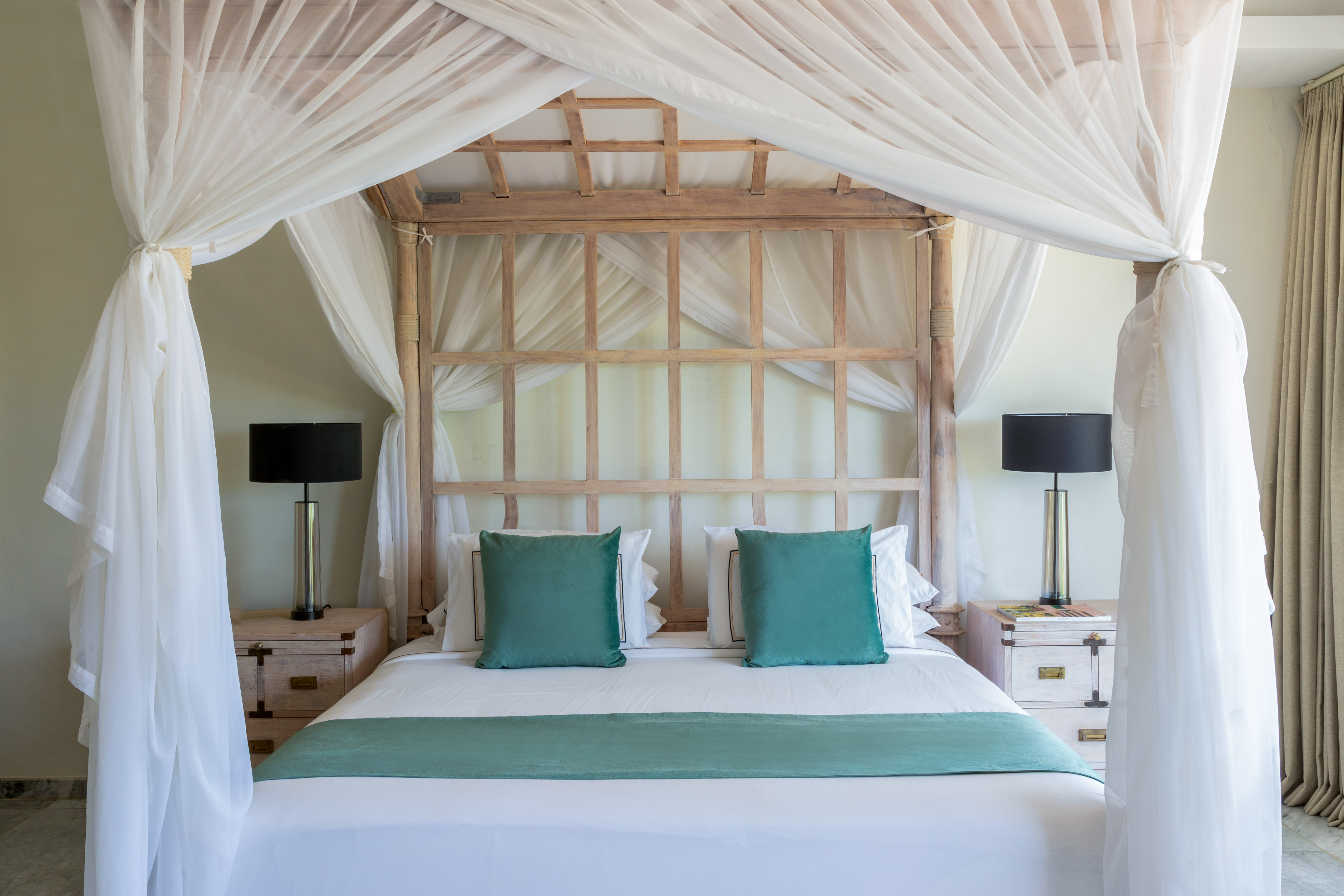 Resort bedroom: wooden four-poster canopy bed, white drapes, teal bedding.