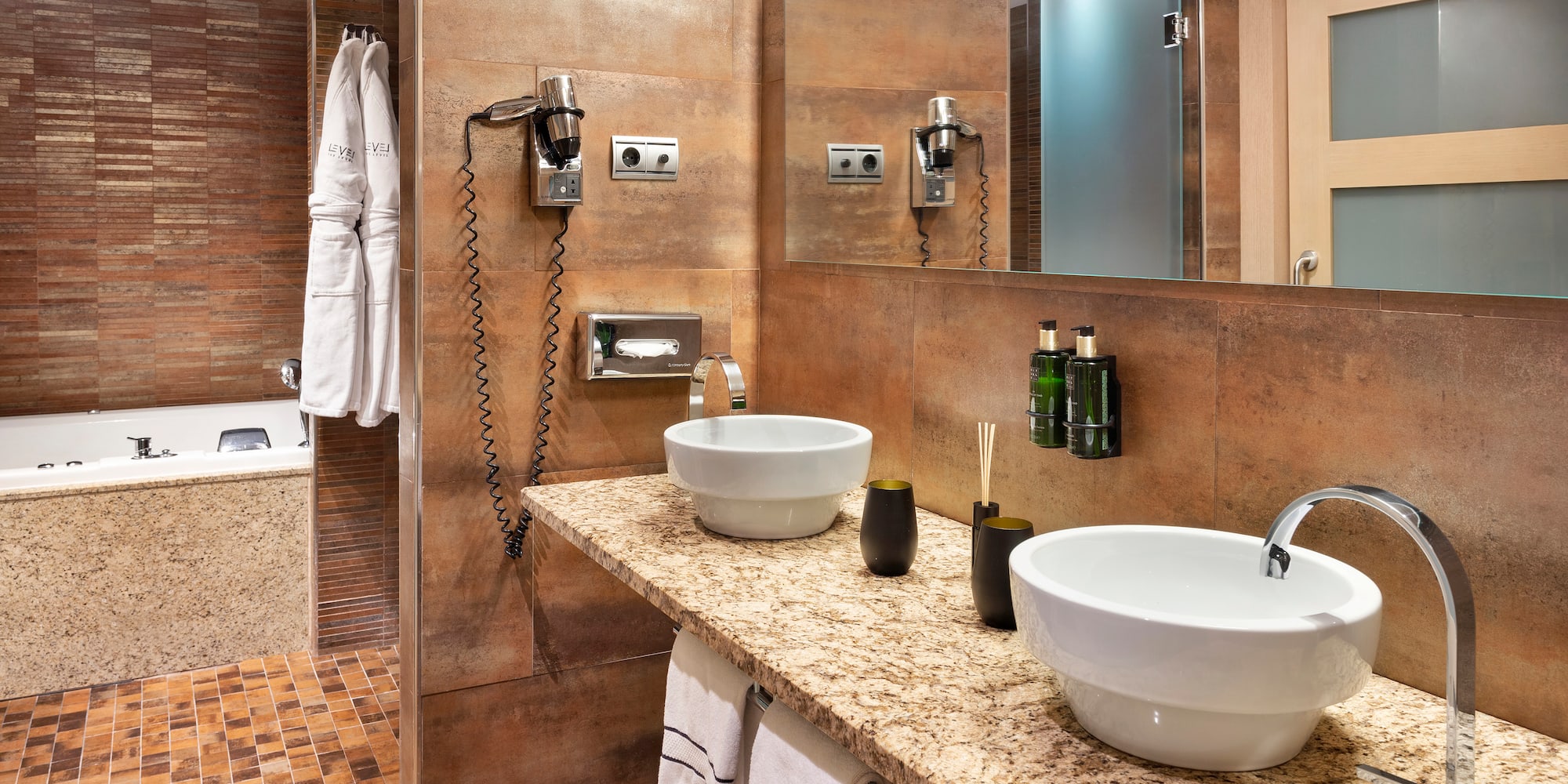 Modern hotel bathroom with dual sinks, granite vanity, and bathtub.