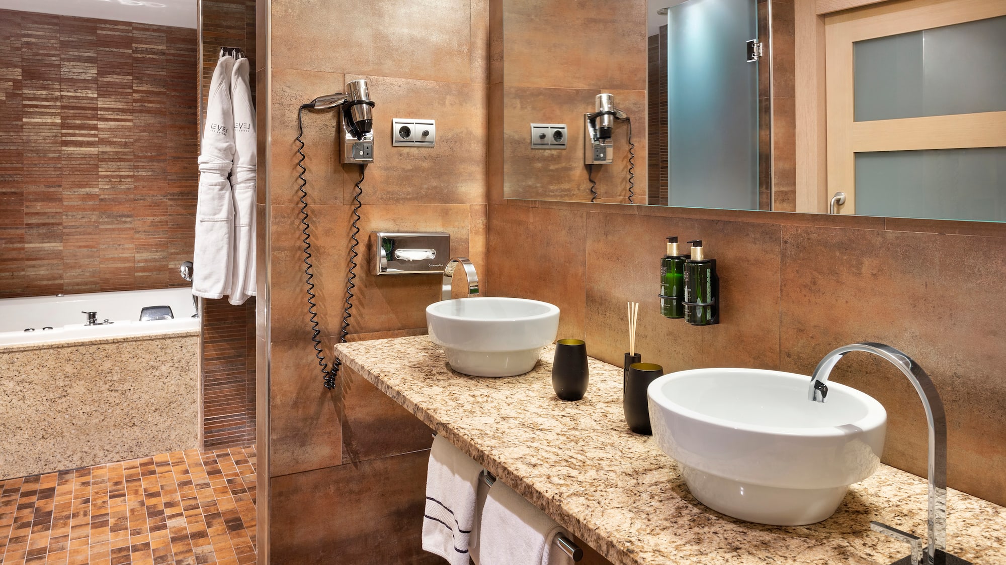 Modern hotel bathroom with dual sinks, granite vanity, and bathtub.