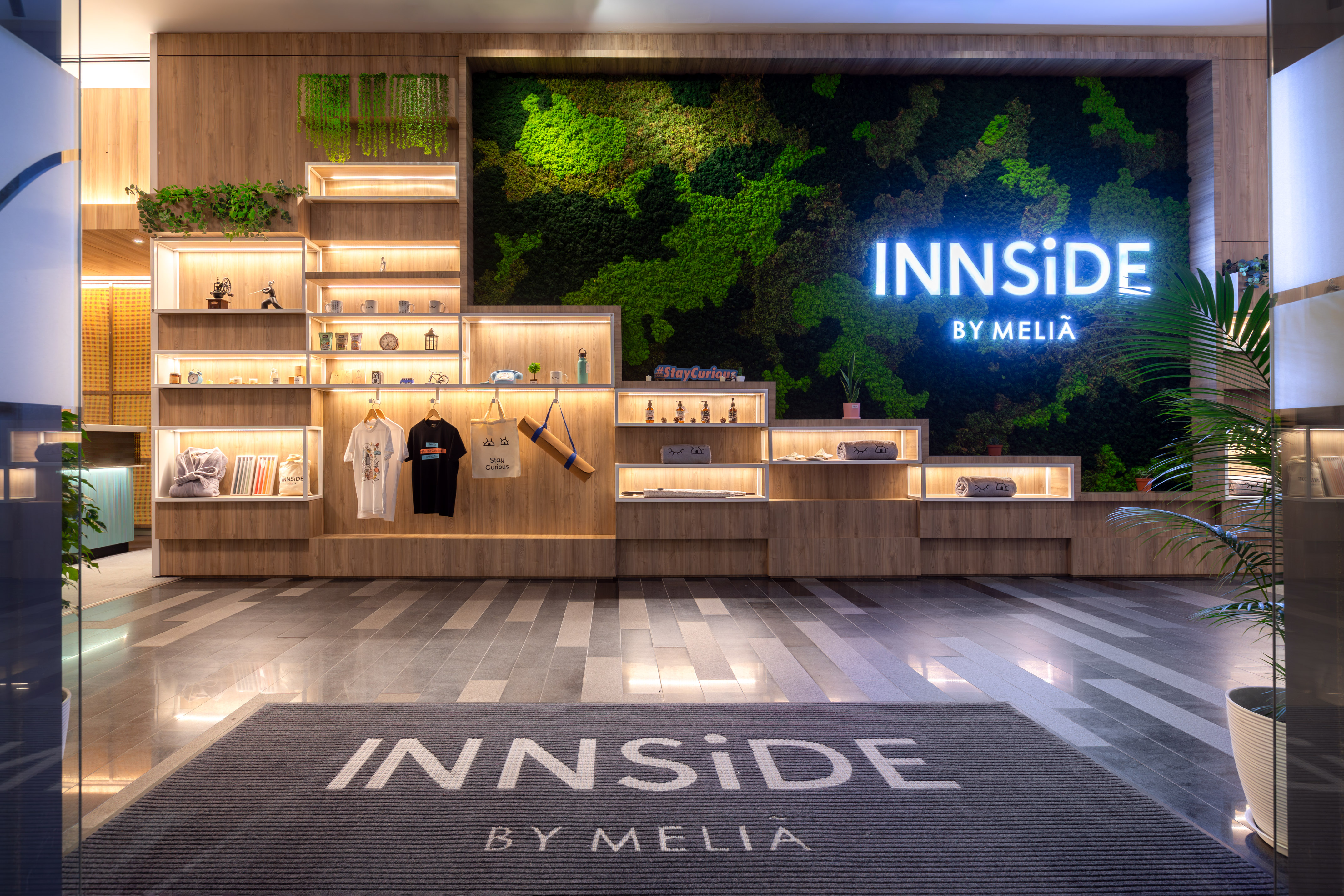 INNSiDE BY MELIÃ modern hotel lobby, moss wall, illuminated sign, wood shelves.