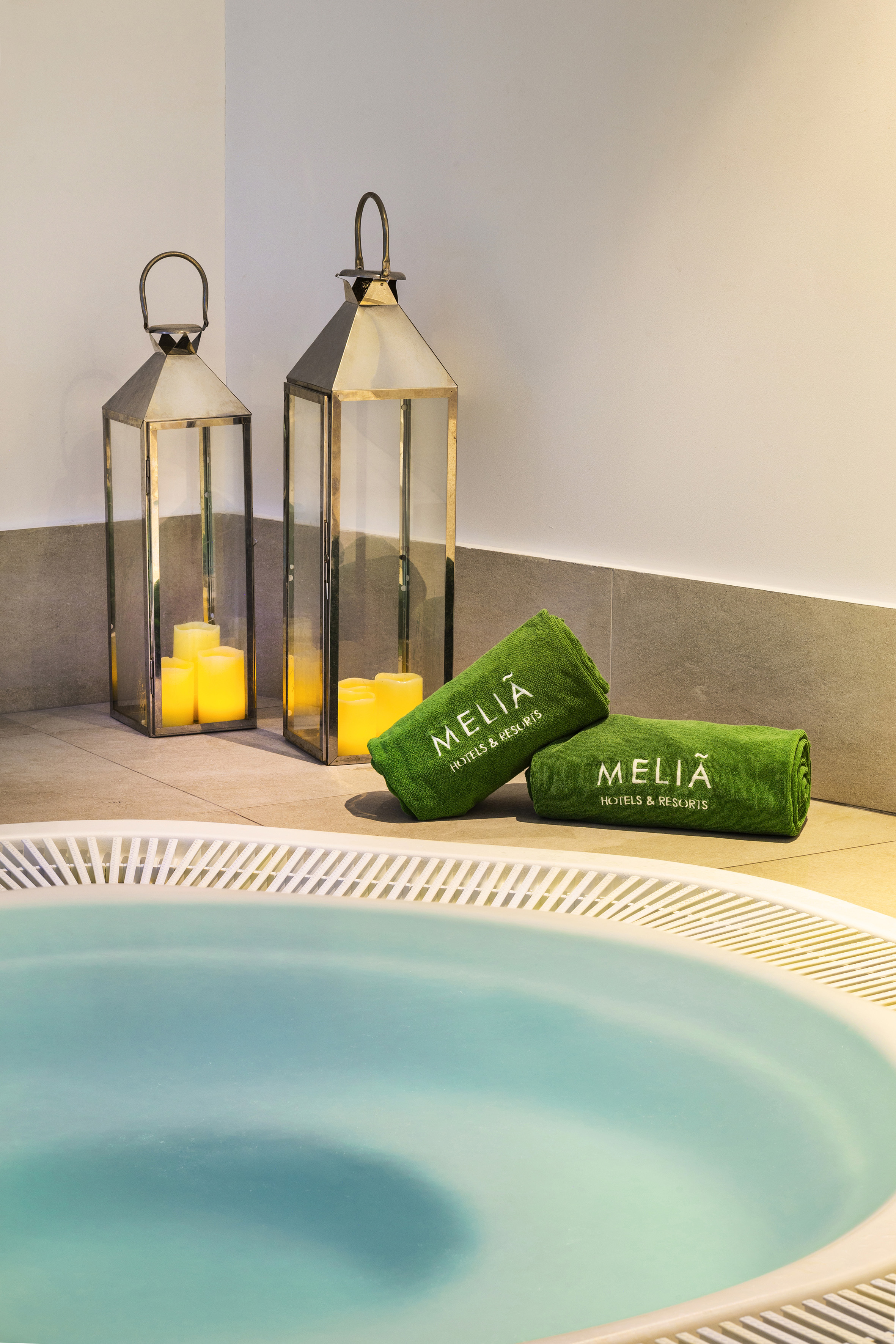 Meliá hotel spa hot tub with green towels and illuminated lanterns.