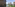 Balcony overlooking sea, resort pool, palm trees, and tall city buildings.