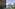 Balcony with clear ocean view, swimming pool, green resort gardens, and buildings.
