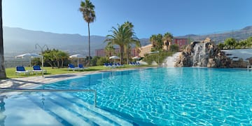 a pool with a waterfall and palm trees