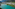 Turquoise mountain lake beside an alpine village with rugged peaks.
