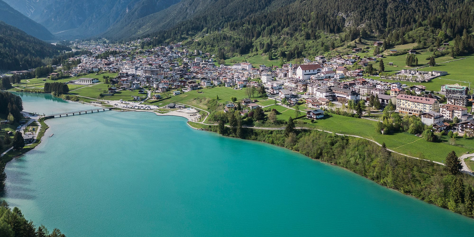 Turquoise mountain lake beside an alpine village with rugged peaks.