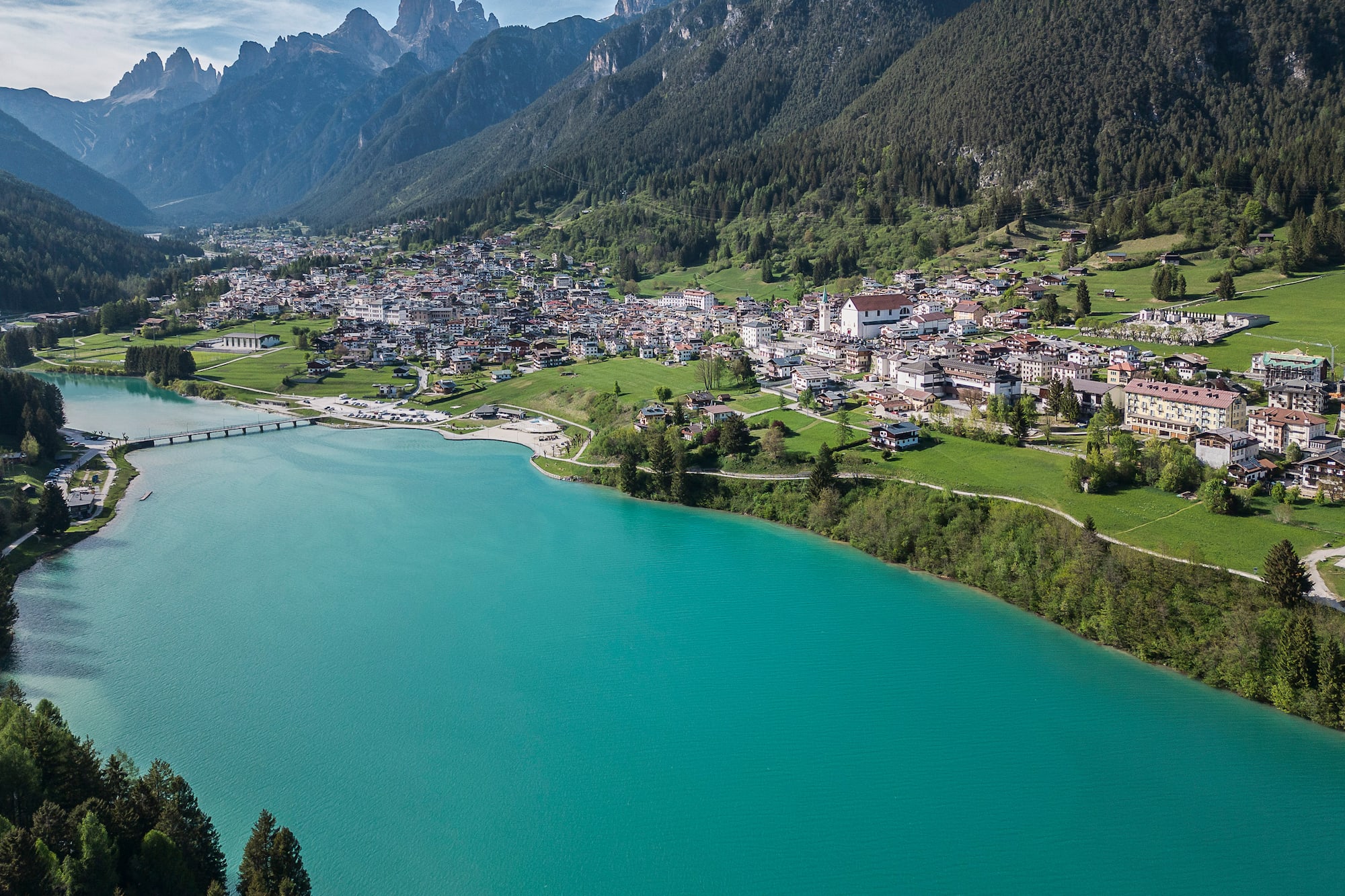 Turquoise mountain lake beside an alpine village with rugged peaks.