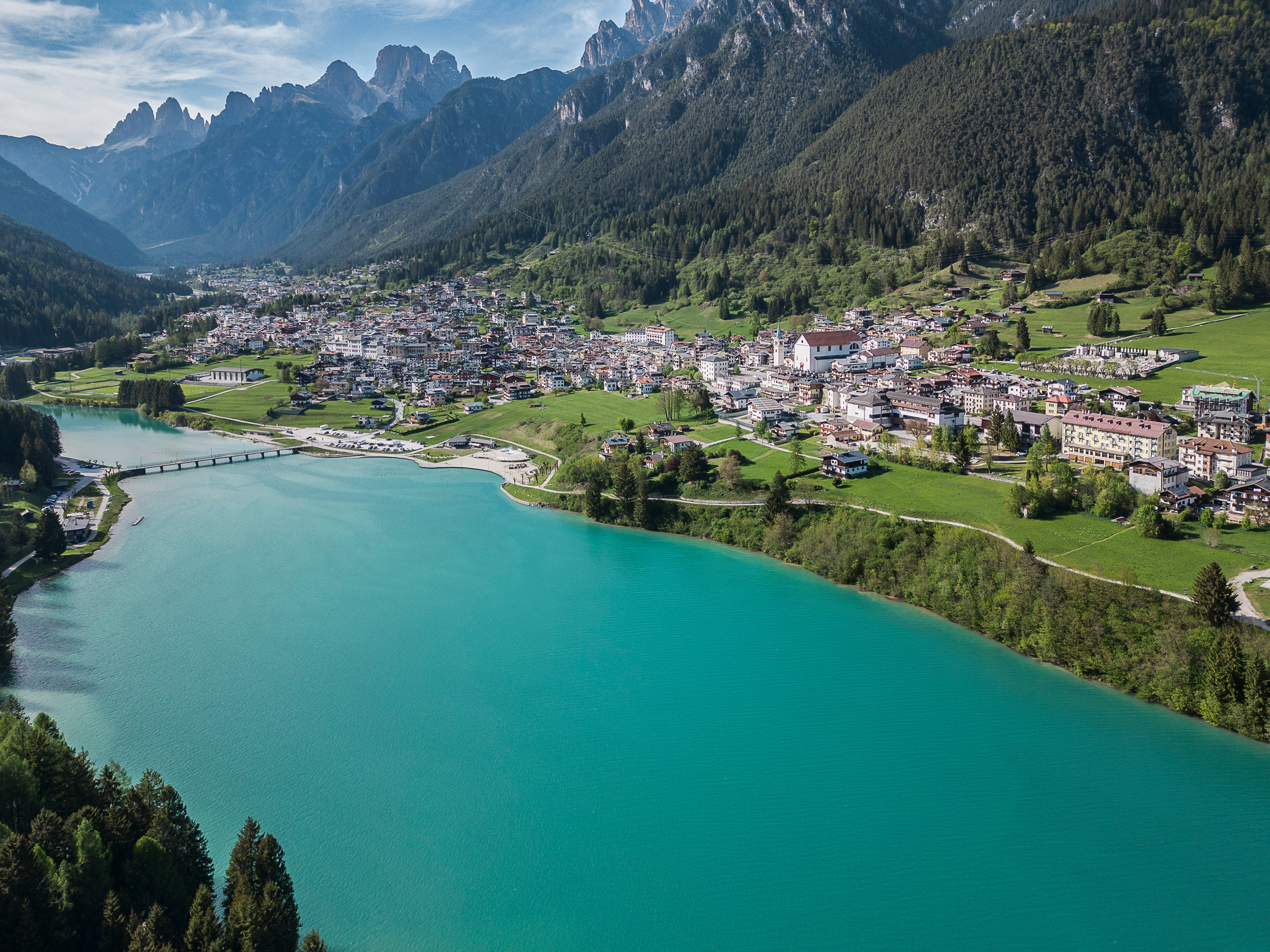 Turquoise mountain lake beside an alpine village with rugged peaks.