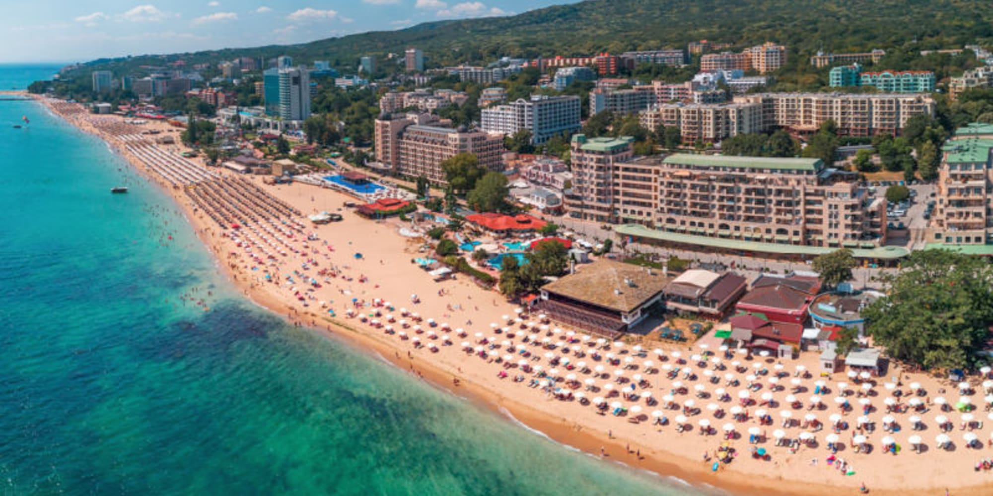 a beach with buildings and umbrellas and buildings on the shore